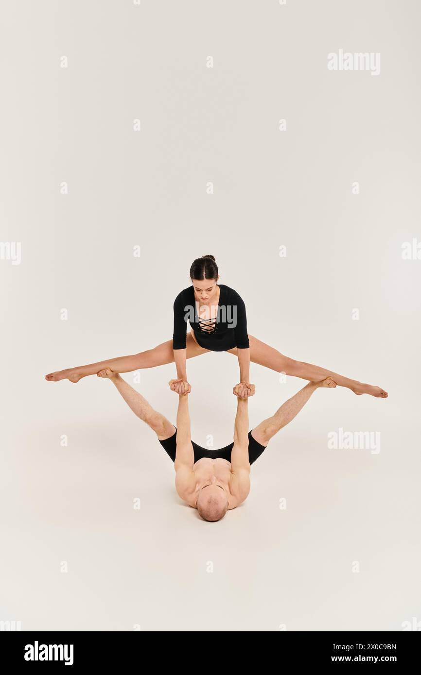 Una donna mostra forza ed equilibrio, eseguendo dei cavalletti sincronizzati in uno studio su uno sfondo bianco. Foto Stock