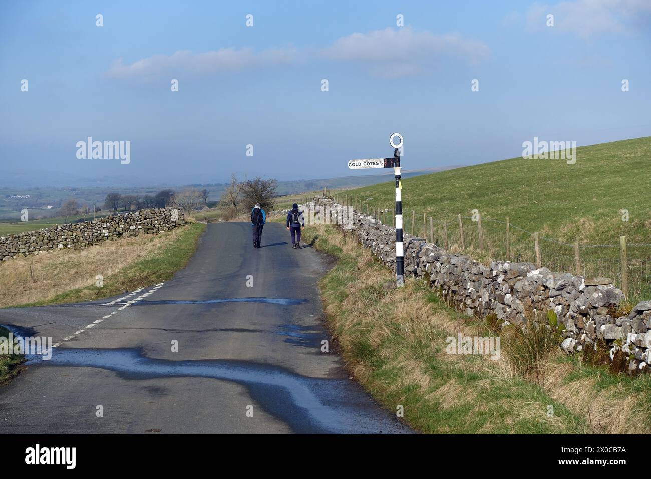 Due uomini che camminano lungo Quiet Country Lane (Old Road) da Clapham a Ingleton vicino a Cold Cotes nello Yorkshire Dales National Park, Inghilterra, Regno Unito Foto Stock