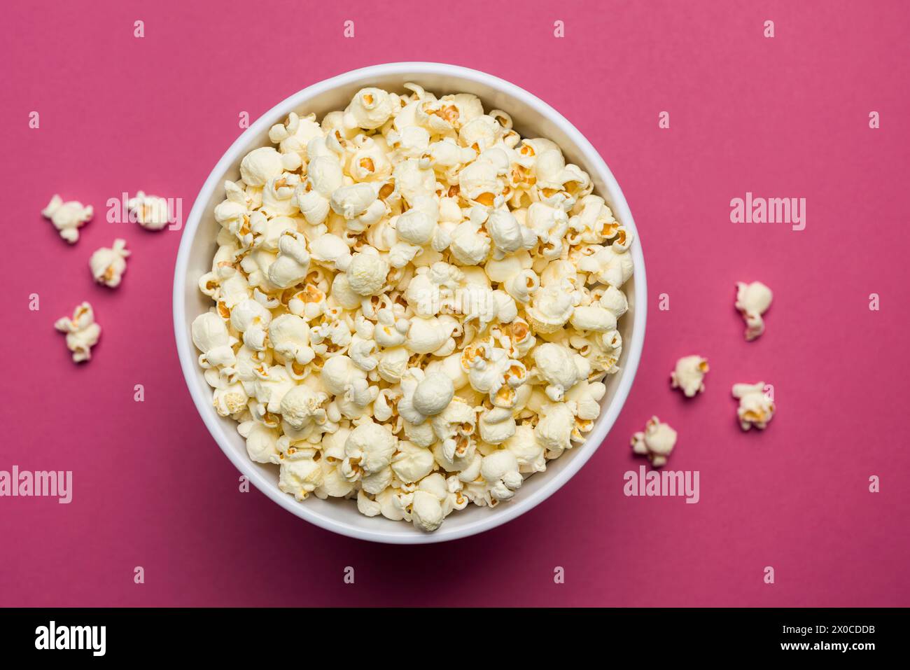 Popcorn salato in secchio classico su sfondo magenta. Foto Stock