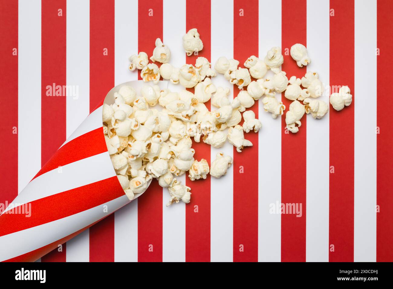 Composizione piatta con popcorn su sfondo a strisce rosse e bianche. Foto Stock