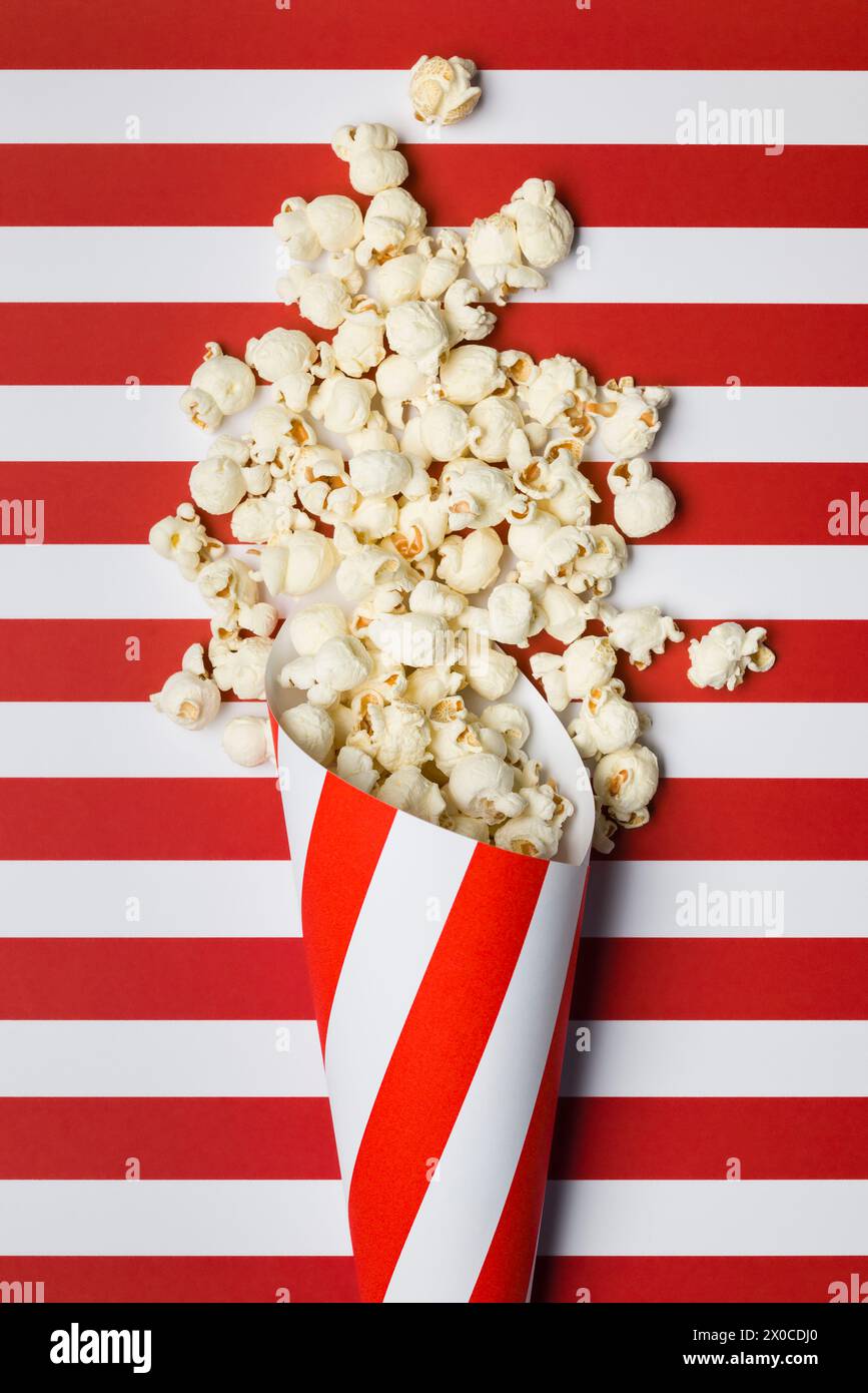 Composizione piatta con popcorn su sfondo a strisce rosse e bianche. Foto Stock