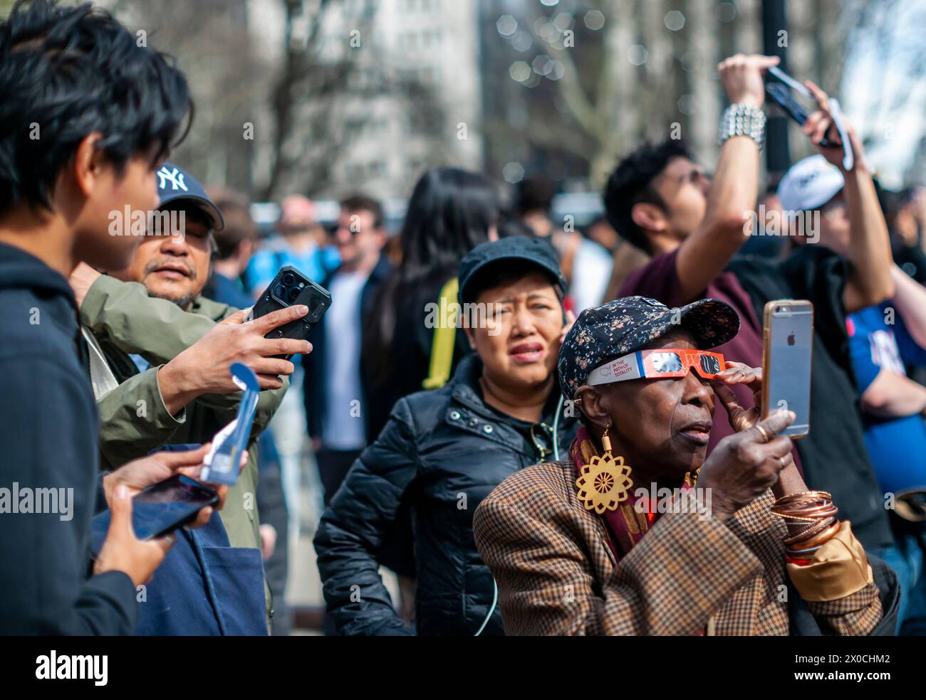 Centinaia di persone si riuniscono al Flatiron Plaza di New York per una festa di osservazione da guardare, indossando la protezione per gli occhi, l'eclissi solare di lunedì 8 aprile 2024. New York City non era nel percorso della totalità con la luna che copriva il 89% del sole durante la finestra dalle 15:15 alle 15:30. (© Richard B. Levine) Foto Stock