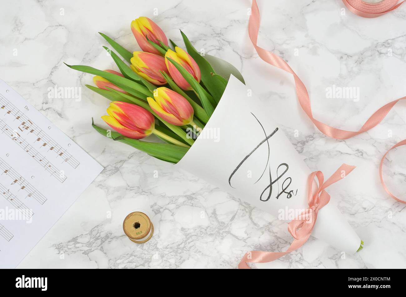 Bouquet di tulipani avvolti in carta con nastro. Spartito di musica, piatto. Foto Stock