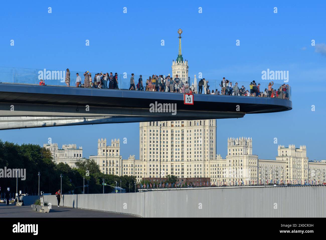 Mosca, Russia - 27 giugno 2018: Le persone si riuniscono sull'iconico ponte galleggiante, offrendo una vista panoramica del maestoso edificio dell'Embankment di Kotelnicheskaya Foto Stock