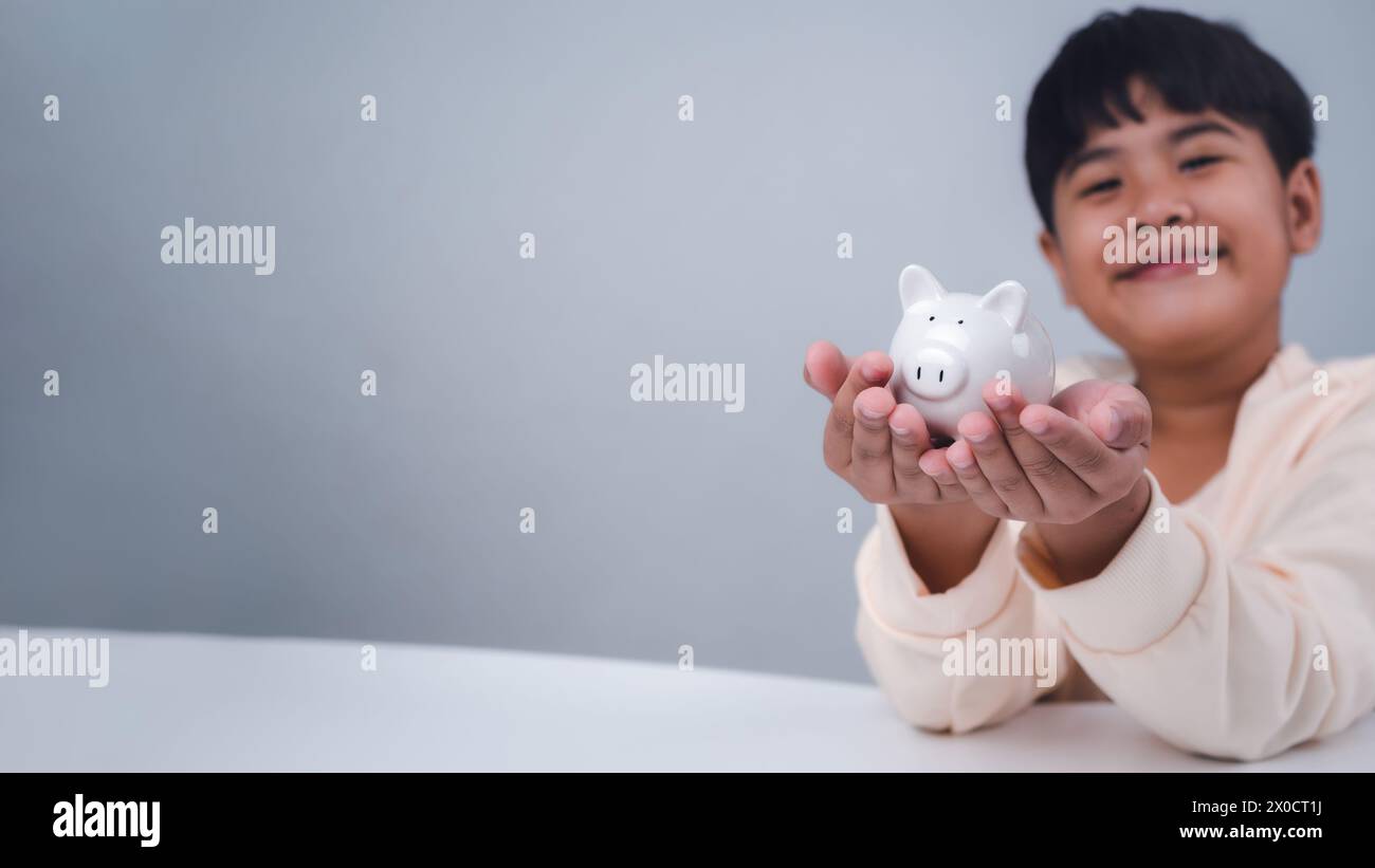 Un ragazzo in possesso di salvadanaio. Apprendere la responsabilità finanziaria e proiettare i risparmi. concetto di risparmio. concetto di investimento. Foto Stock