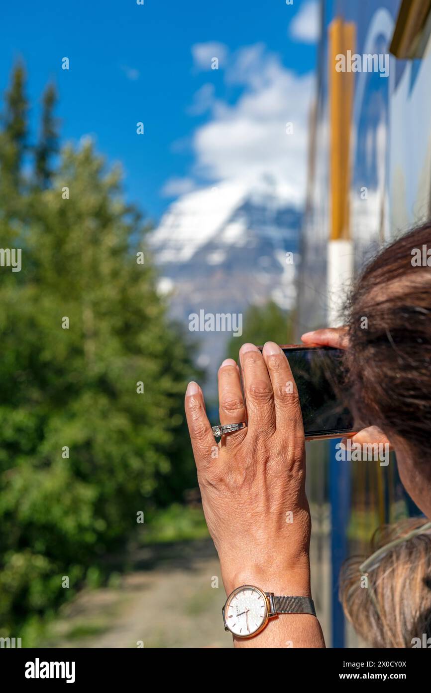 Donna che scatta fotografie del monte Robson dal vagone ferroviario Rocky Mountaineer, British Columbia, Canada. Foto Stock