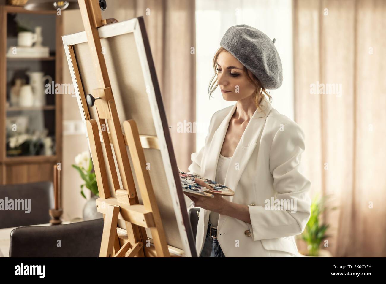 Bella pittrice che si diverte mentre dipinge in uno studio d'arte domestico. Woman Artist lavora sulla pittura acrilica astratta nello studio d'arte. Foto Stock