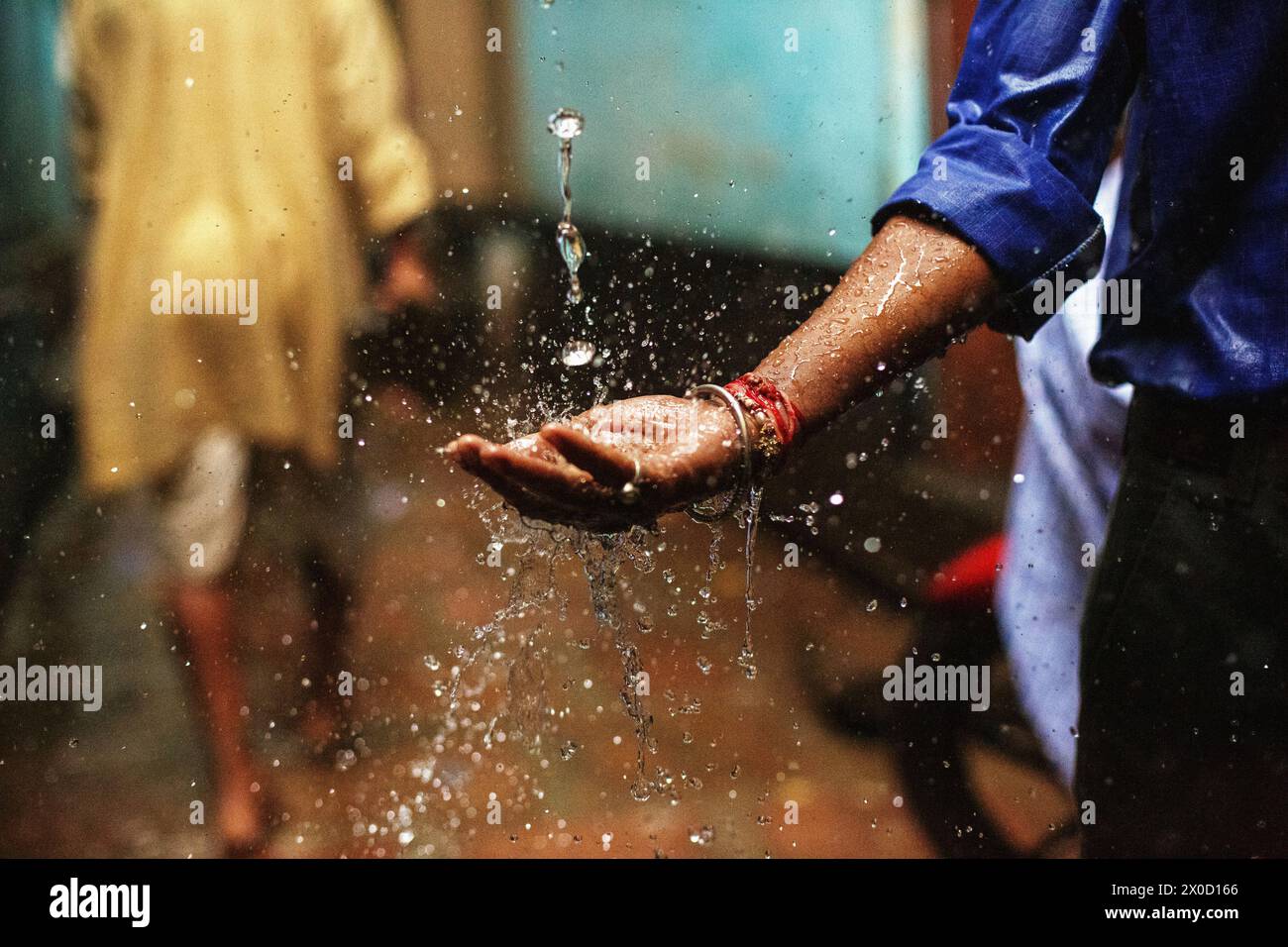 Uomo che cattura pioggia durante la stagione dei monsoni a Varanasi, India. Foto Stock