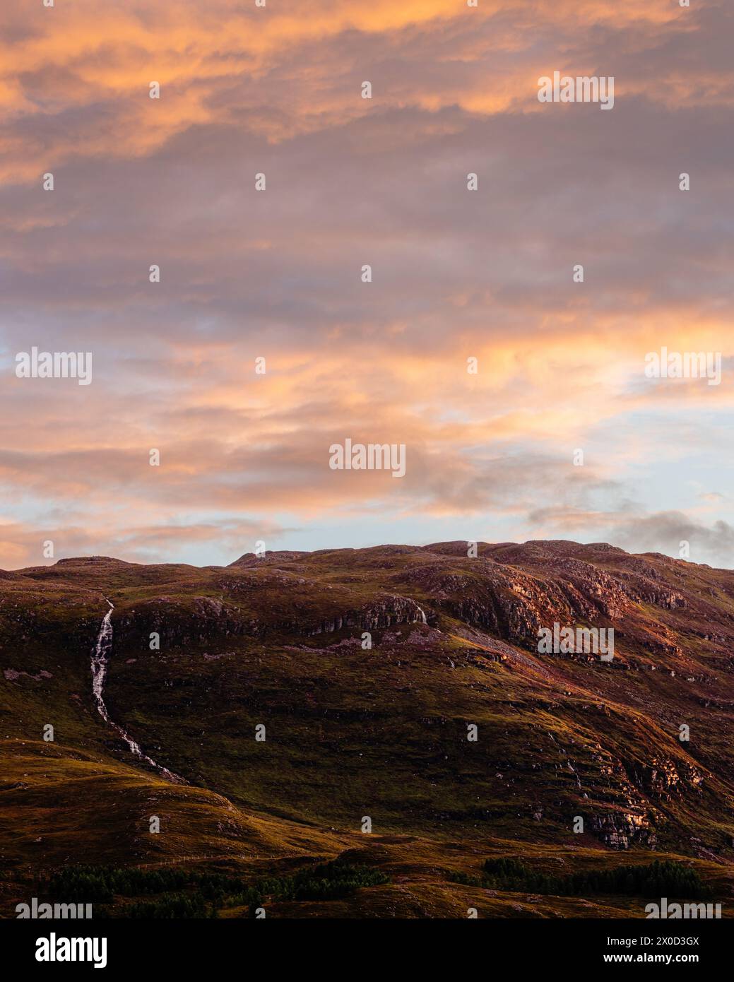 Cascata d'acqua dopo forti piogge sul lato di Beinn Gharbh, Assynt. Al tramonto. Foto Stock