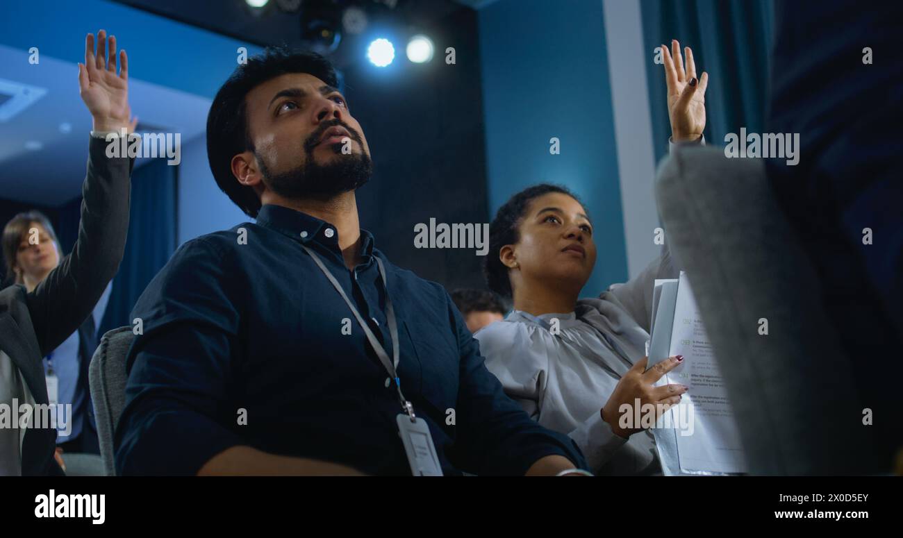 Nella sala conferenze siedono addetti stampa multietnici. Il giornalista indiano maschile alza la mano, fa domande e scrive la risposta durante la campagna stampa con un rappresentante dell'organizzazione o un politico. Foto Stock