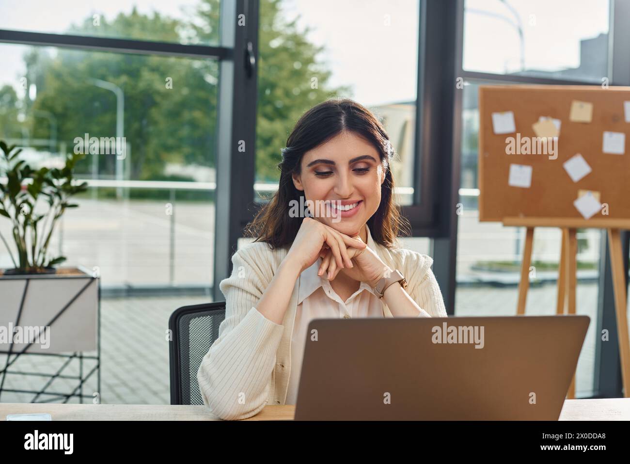 Una donna d'affari siede di fronte a un computer portatile in un ufficio moderno, concentrandosi sul suo lavoro in franchising. Foto Stock