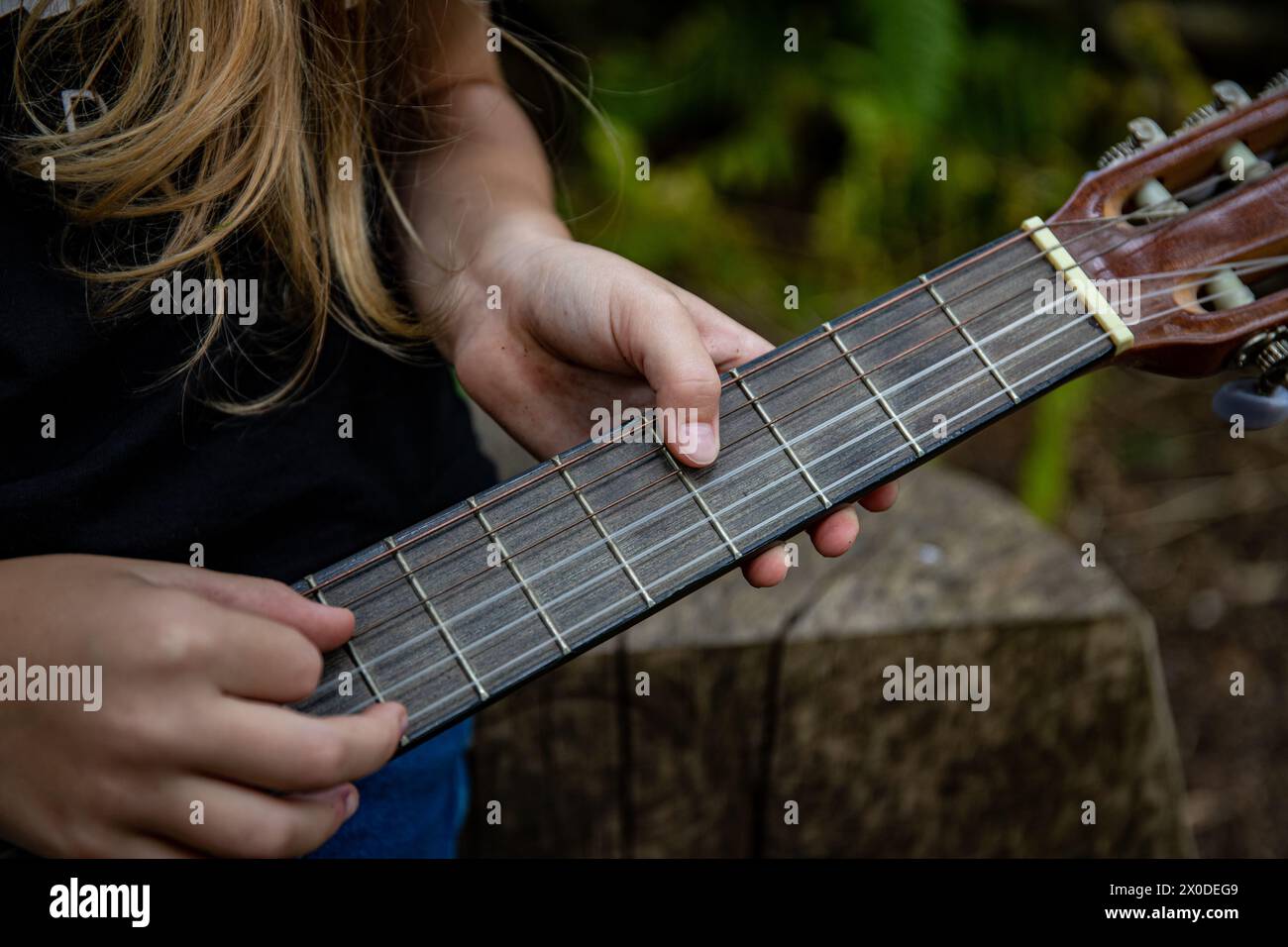 Bambino che tiene in mano una chitarra in legno nella foresta naturale Foto Stock