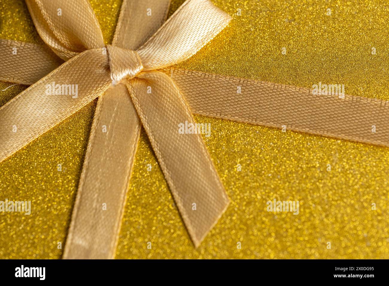 Confezione regalo oro con fiocco e fiocco su sfondo dorato lucido. Vista dall'alto Foto Stock