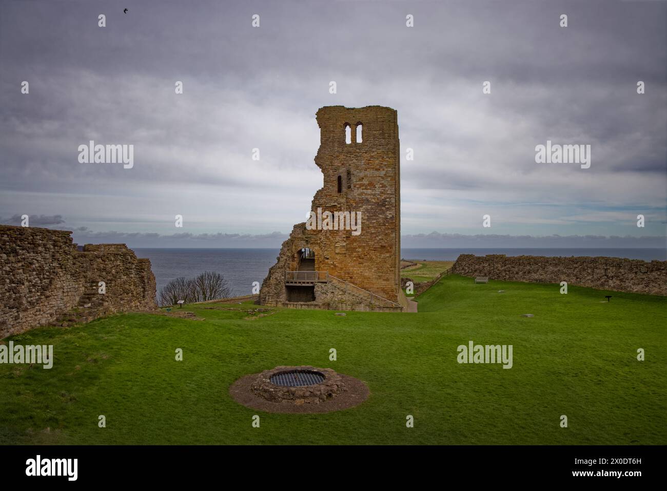 Un castello in rovina mantiene la torre con ben in un prato in primo piano e il mare oltre, il castello di Scarborough, North Yorkshire, Inghilterra. Foto Stock