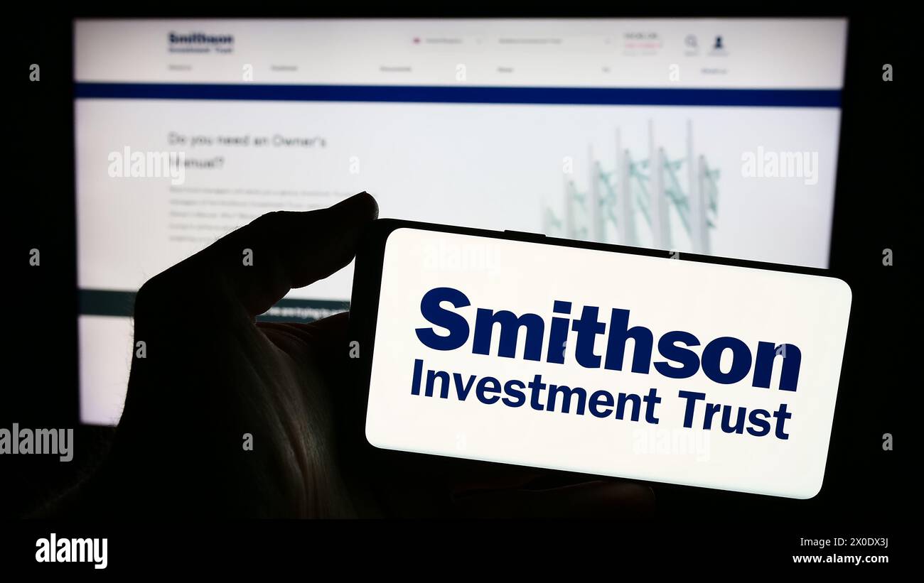 Persona che detiene uno smartphone con il logo della società britannica Smithson Investment Trust plc davanti al sito Web. Mettere a fuoco il display del telefono. Foto Stock