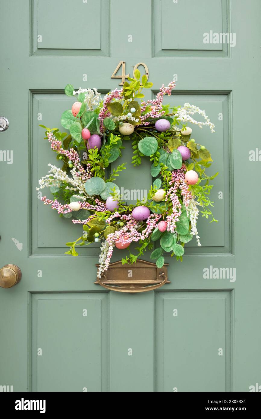Ghirlanda di Pasqua in plastica kitsch con decorazioni di uova di Pasqua dipinte in pastello artificiali su una porta d'ingresso verde nel Galles Ceredigion Regno Unito KATHY DEWITT Foto Stock