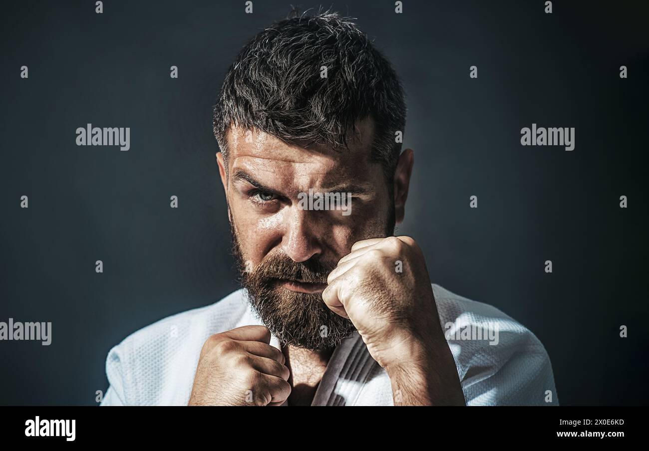 Primo piano ritratto di un serio uomo di karate in kimono bianco. Maestro di arti marziali in posizione di combattimento. Lottatore di karate in preparazione alla competizione. Forte Foto Stock