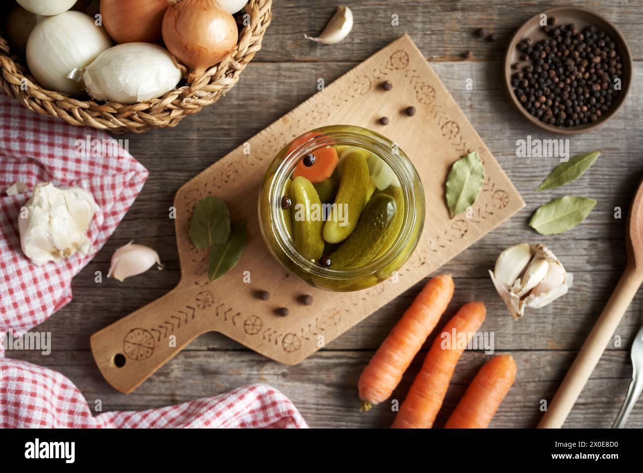 Sottaceti o cetrioli fatti in casa in un vaso di vetro su un tavolo con verdure e spezie, vista dall'alto Foto Stock