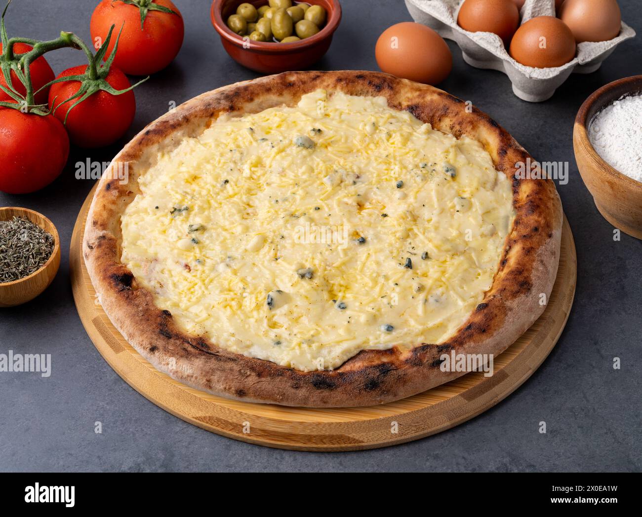 Quattro pizze in stile formaggio su fondo in pietra con pomodori, olive e origano. Foto Stock