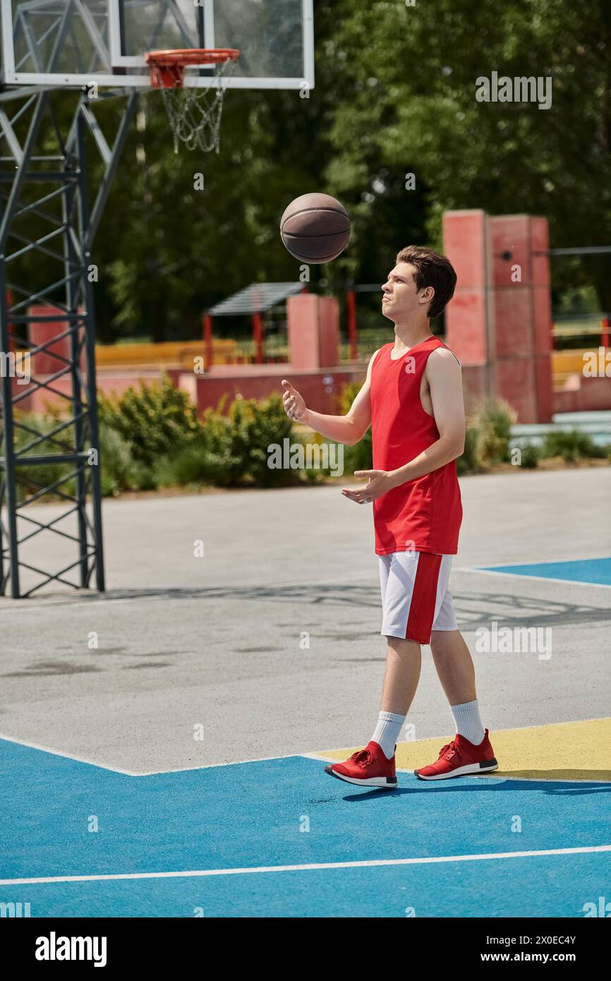 Un giovane tira un pallacanestro su un campo illuminato dal sole, mostrando le sue abilità e la sua passione per il gioco. Foto Stock