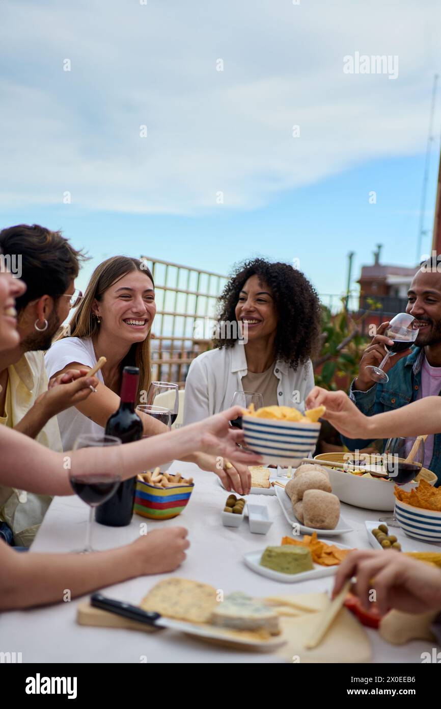 Gruppo di giovani amici multietnici che gusteranno il pasto riuniti sul tetto Foto Stock