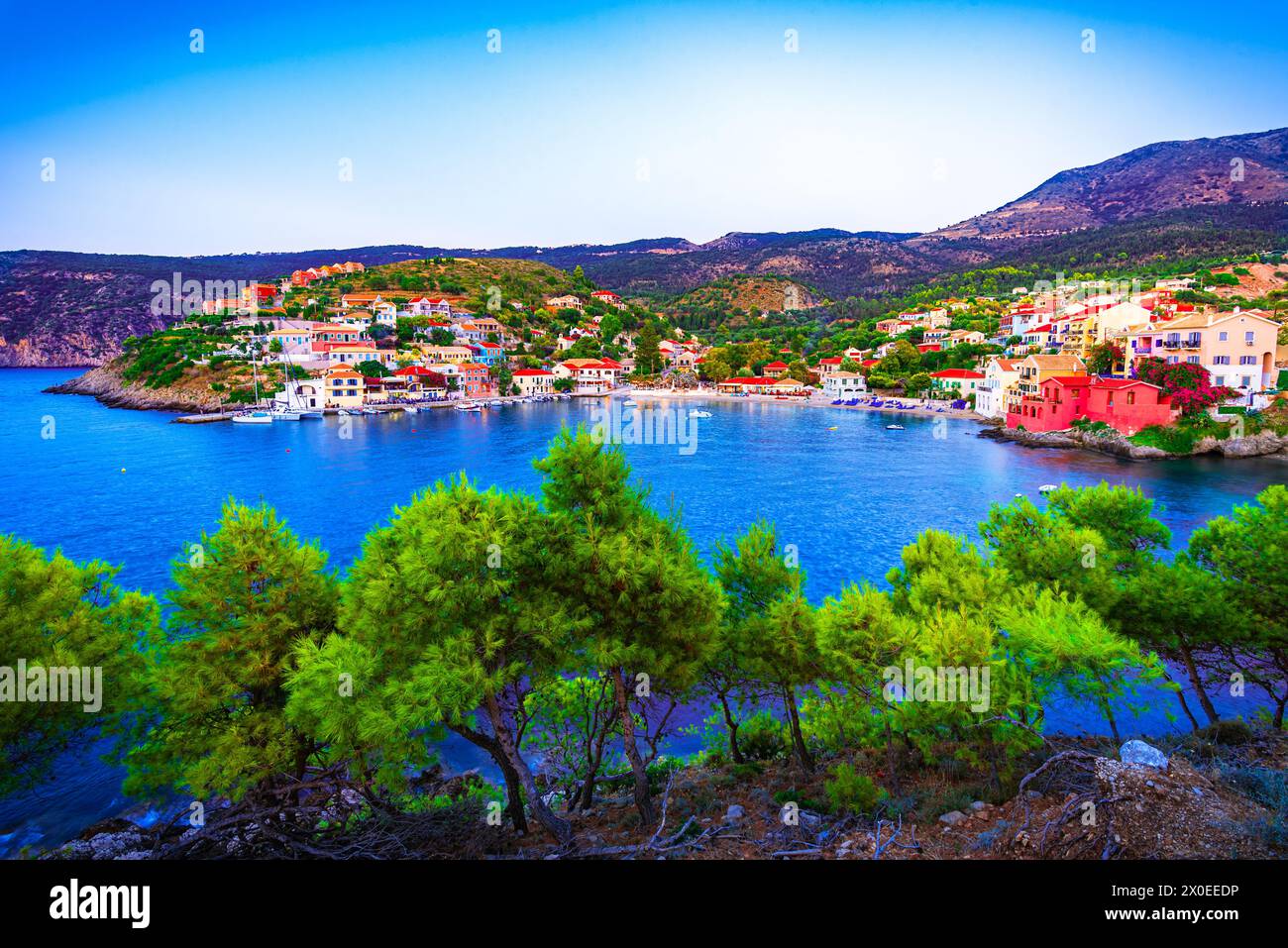 Assos, Cefalonia, Grecia. Case colorate e baia dai colori turchesi di un villaggio su un'idilliaca isola ionica, in Europa Foto Stock