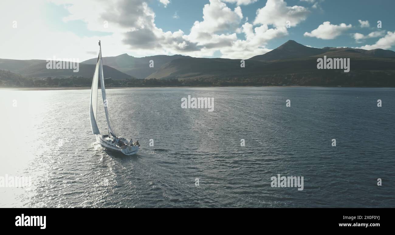 Baia del sole con volo di regata di yacht. Tranquillo paesaggio marino con lussuosa barca a vela che riflette il golfo dell'oceano. Vacanze estive in barca a vela. Concetto di turismo e viaggio. Ripresa cinematografica con drone a luce soffusa Foto Stock