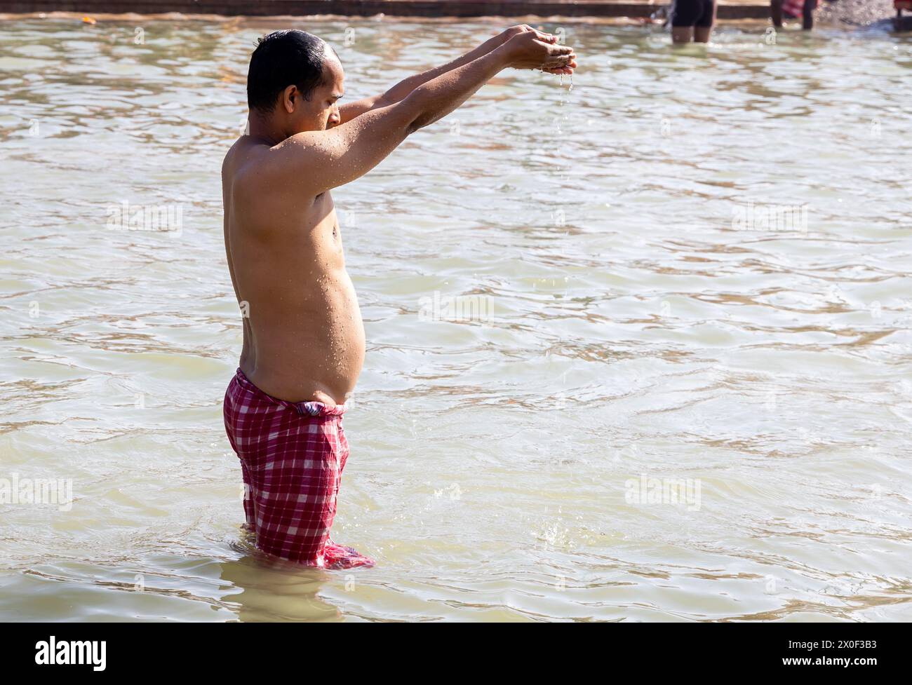 giovane devoto che prega per il santo dio dopo aver fatto il bagno nell'acqua santa del fiume al mattino da un angolo piatto Foto Stock
