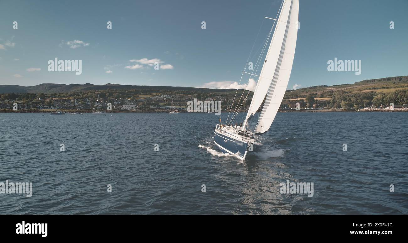 Yacht da regata sull'antenna di Sun Ocean Bay. Nessun paesaggio naturale dell'isola di Arran. Il paesaggio urbano di Brodick, nel verde dell'altopiano. Vista marina della Scozia cinematografica con trasporto d'acqua al drone Foto Stock