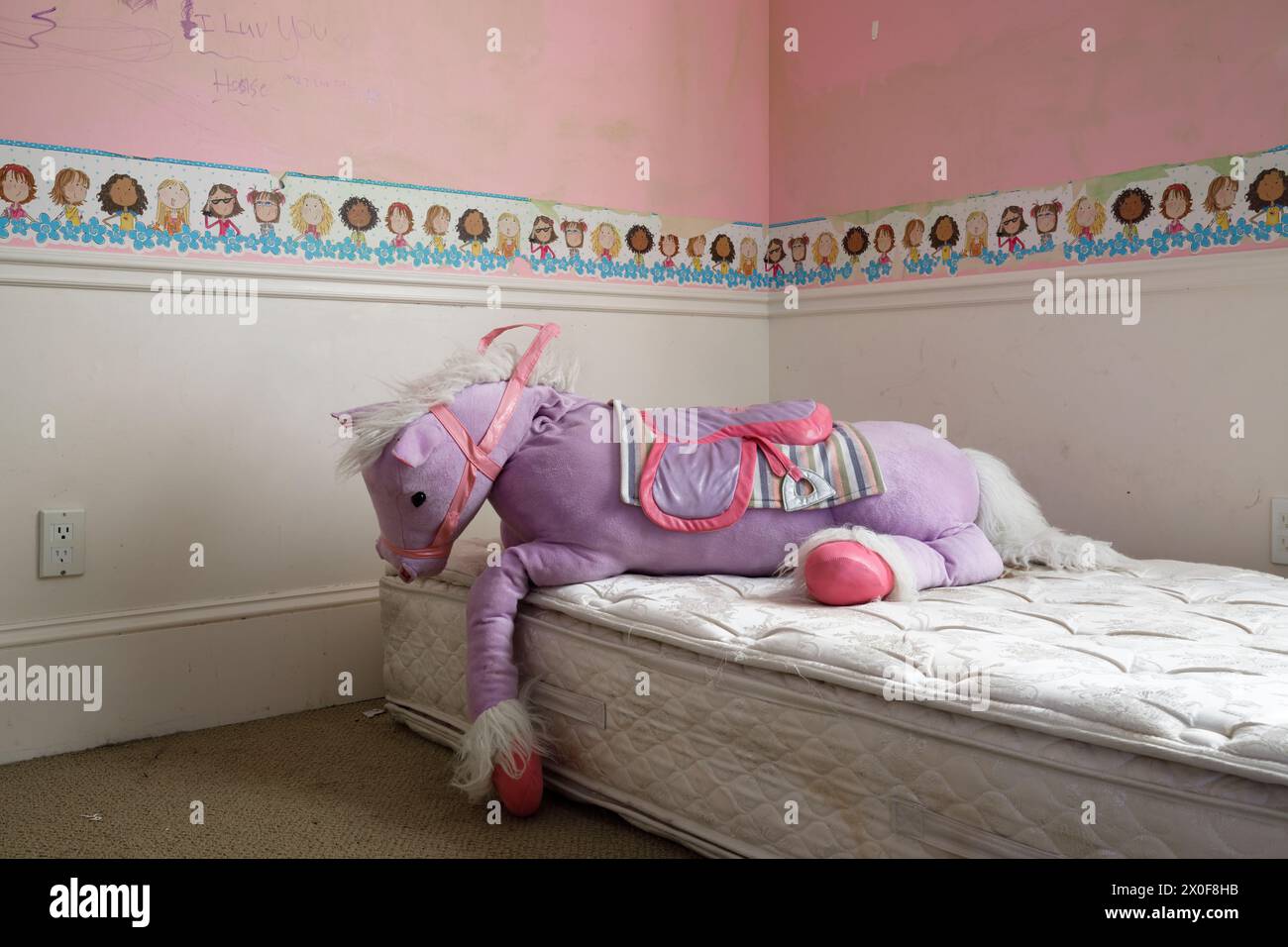 Una stanza per bambini con un animale da cavallo imbottito all'interno di una casa abbandonata. Foto Stock