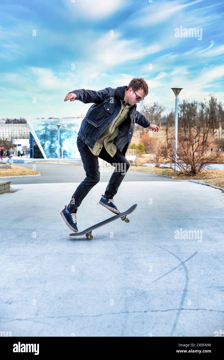 Giovane che cavalca uno skateboard facendo trucchi e salti Foto Stock