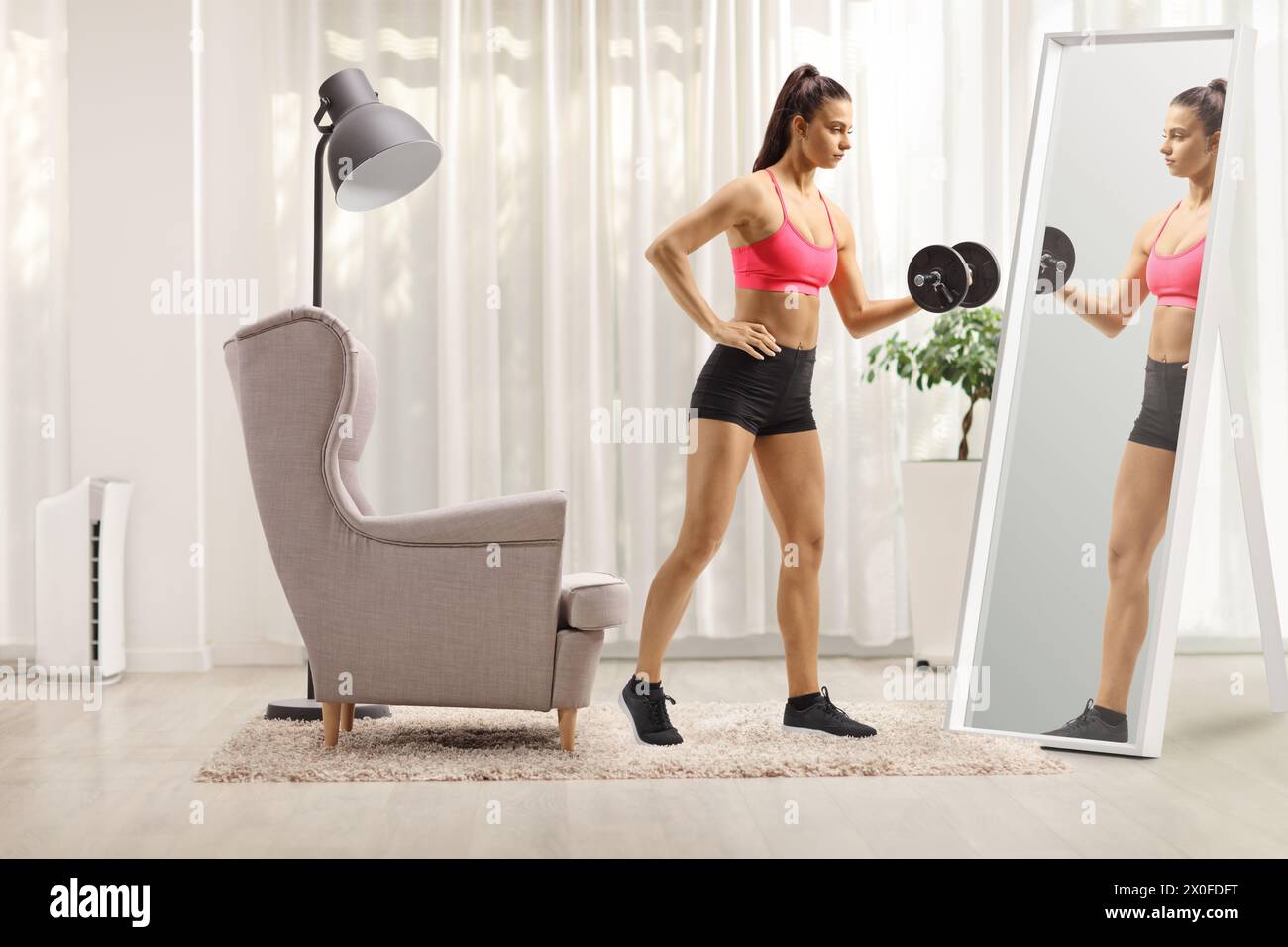 Adatta la giovane donna che esercita l'allenamento con il peso con un manichino davanti a uno specchio Foto Stock