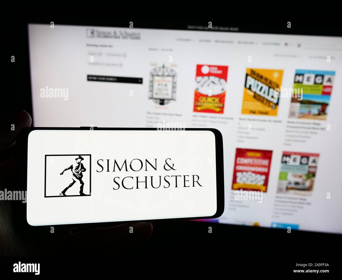 Persona che possiede uno smartphone con il logo della casa editrice statunitense Simon and Schuster LLC davanti al sito web. Mettere a fuoco il display del telefono. Foto Stock