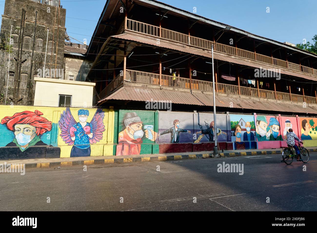 Una lunga parete a Mumbai, India, situata di fronte ad un edificio storico e decorata con colorati murales a tema Covid-19 Foto Stock