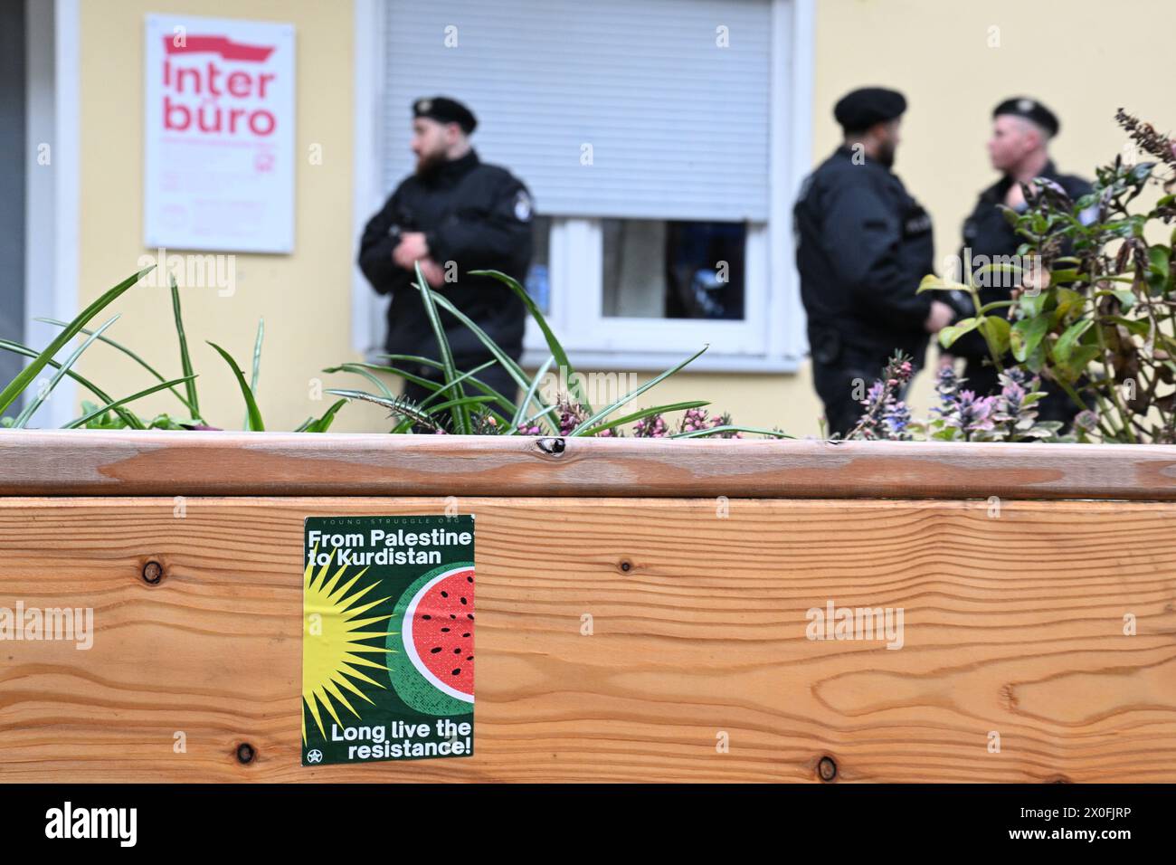 Berlino, Germania. 12 aprile 2024. Gli agenti di polizia stanno dietro un adesivo con la scritta "dalla Palestina al Kurdistan lunga vita alla resistenza!” Prima dell'inizio di una conferenza stampa sul Congresso palestinese 2024 a Berlino, davanti al negozio dove si svolgerà. (Dalla Palestina al Kurdistan, lunga vita alla resistenza!) L'evento pro-palestinese con il motto "denunciamo” si svolgerà dal 12 al 14 aprile. Dall'annuncio del congresso, si sono ripetute dure critiche. Crediti: Sebastian Christoph Gollnow/dpa/Alamy Live News Foto Stock