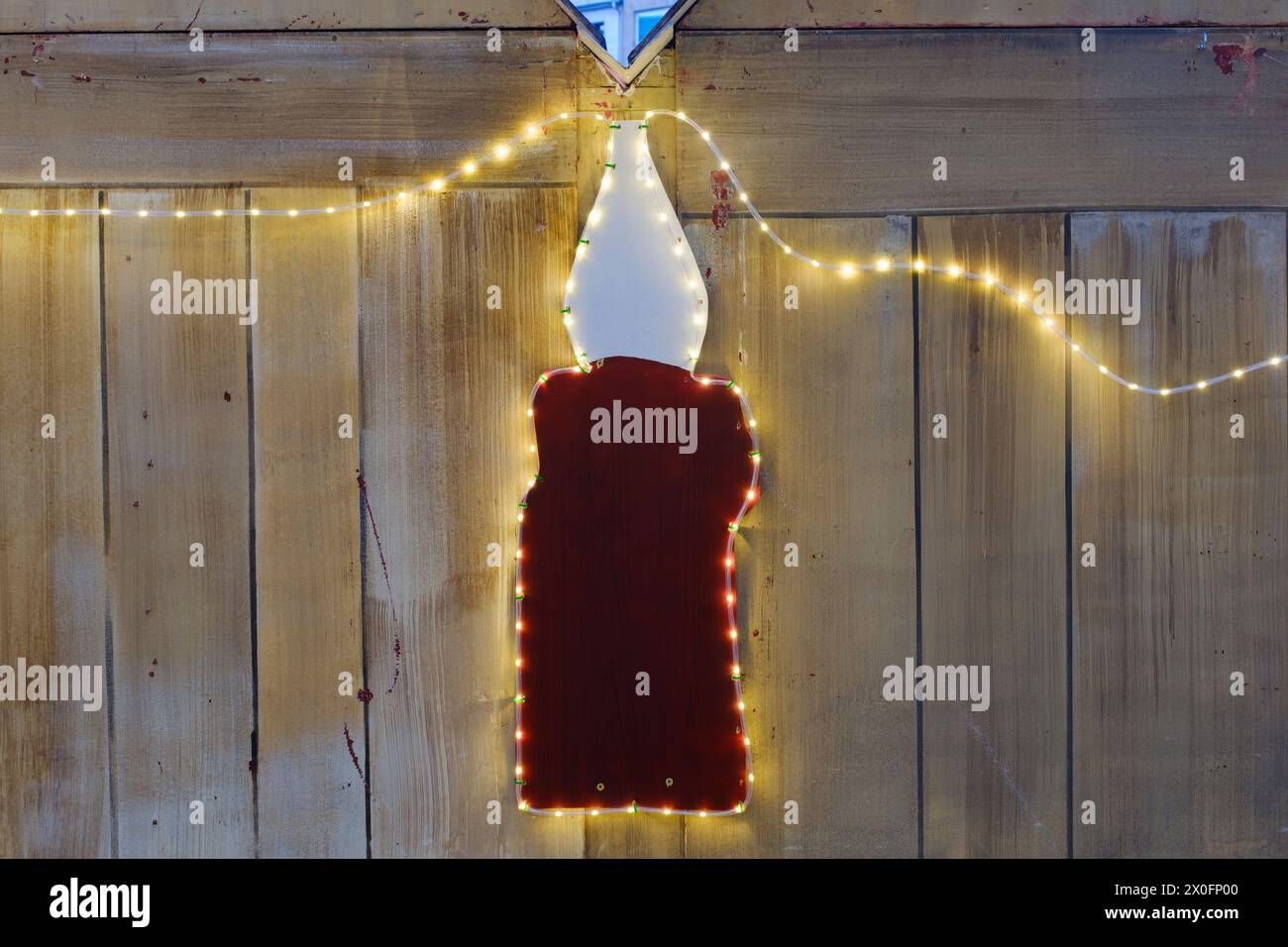 Candela illuminata di fronte a un muro di legno Foto Stock