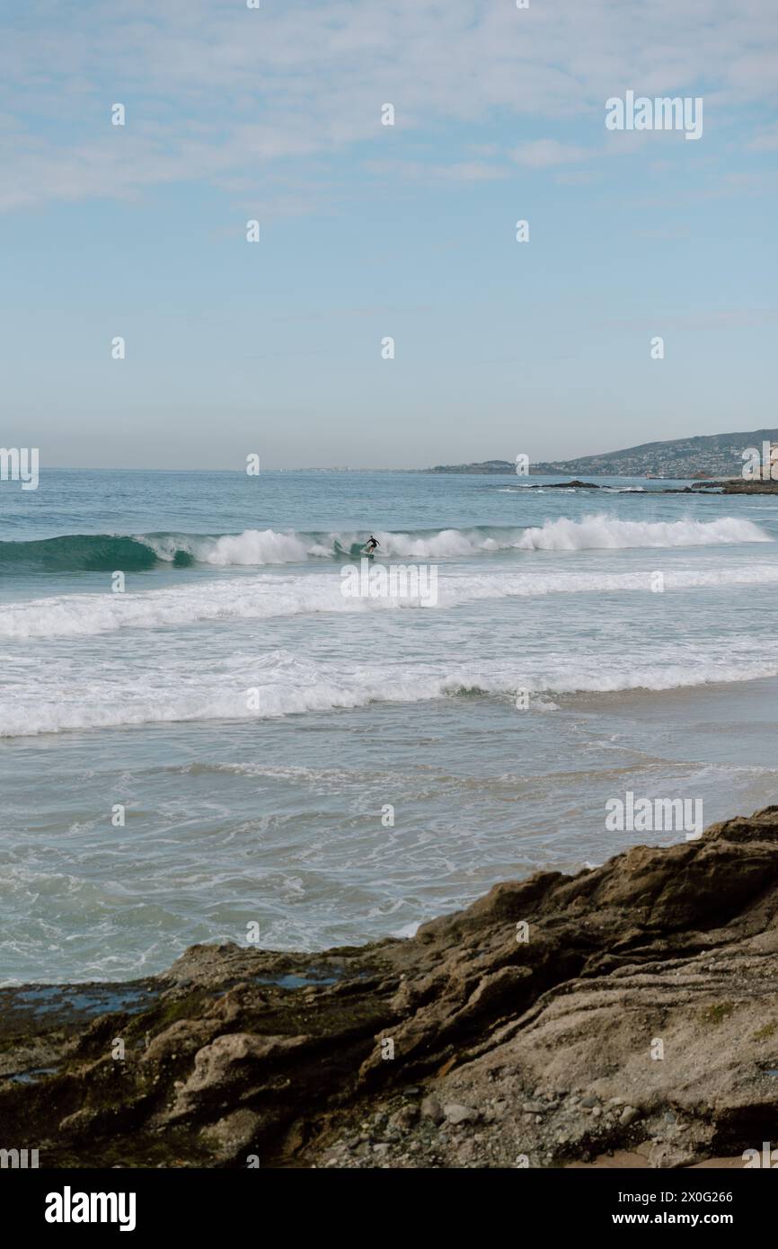 Uomo che fa surf sulle onde che si infrangono sulla spiaggia in California Foto Stock