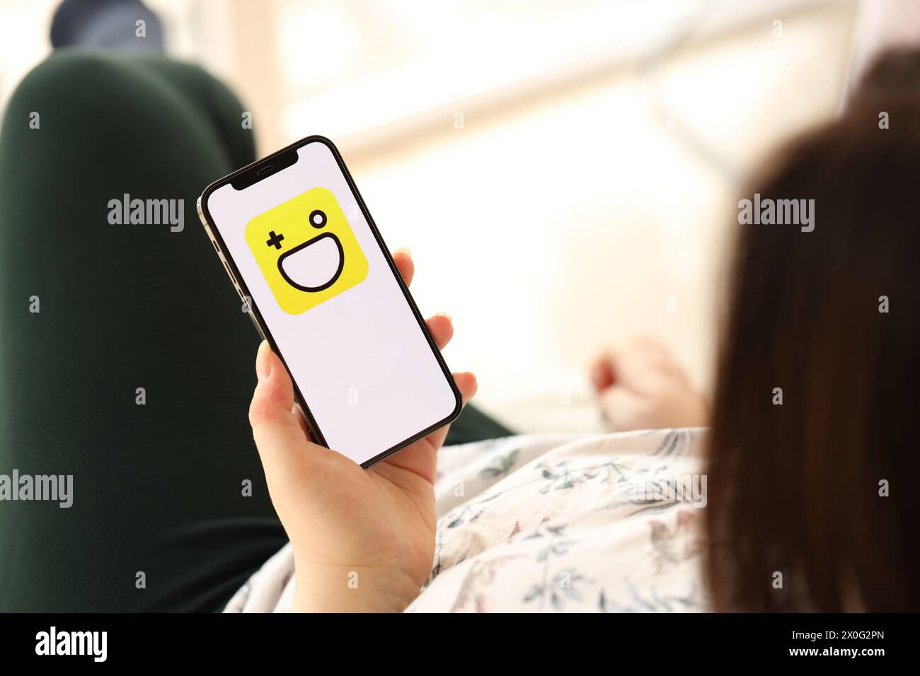 KIEV, UCRAINA - 1 APRILE 2024 icona di Hago sullo schermo dello smartphone in giovani mani femminili al chiuso. Donna che usa l'app per iPhone a casa Foto Stock