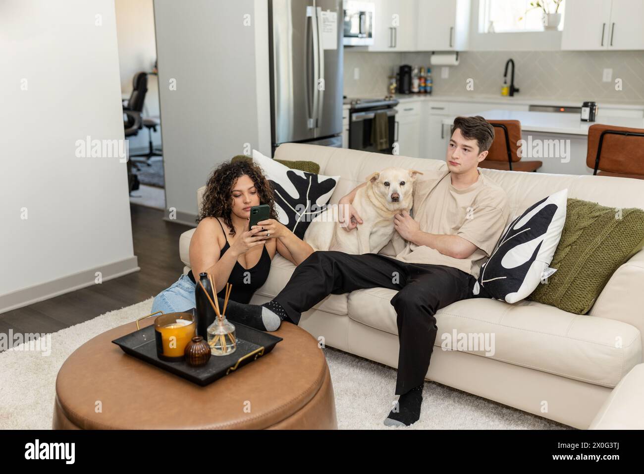 La coppia si rilassa con il suo fedele cane, donna che naviga sul telefono Foto Stock