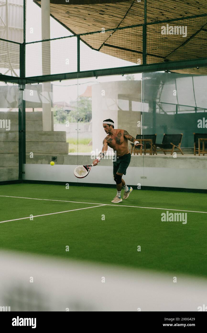 L'uomo gioca a tennis su un campo al coperto, Bali. Foto Stock