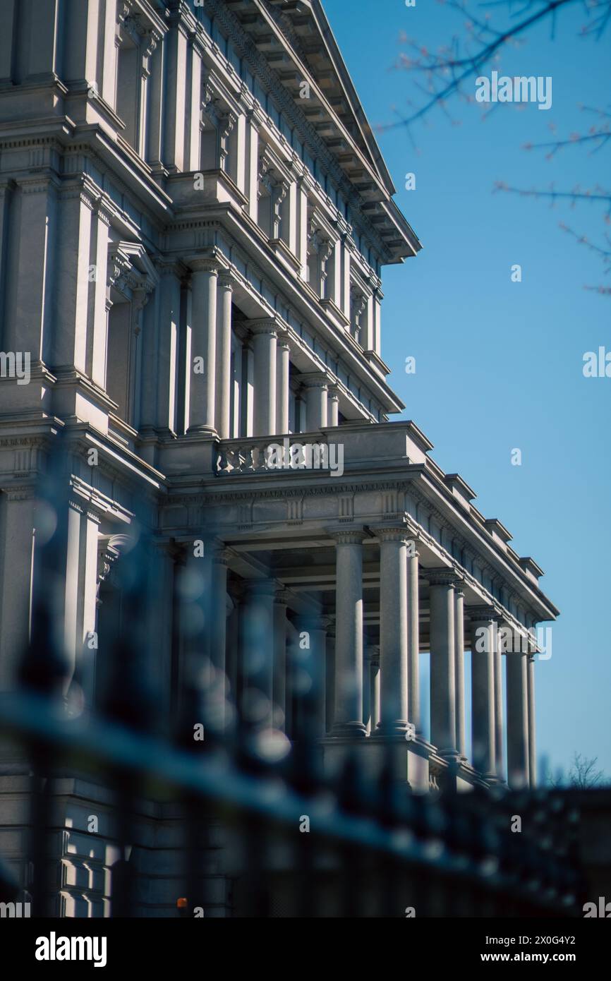 Edificio grigio con colonne e un cancello sfocato davanti Foto Stock