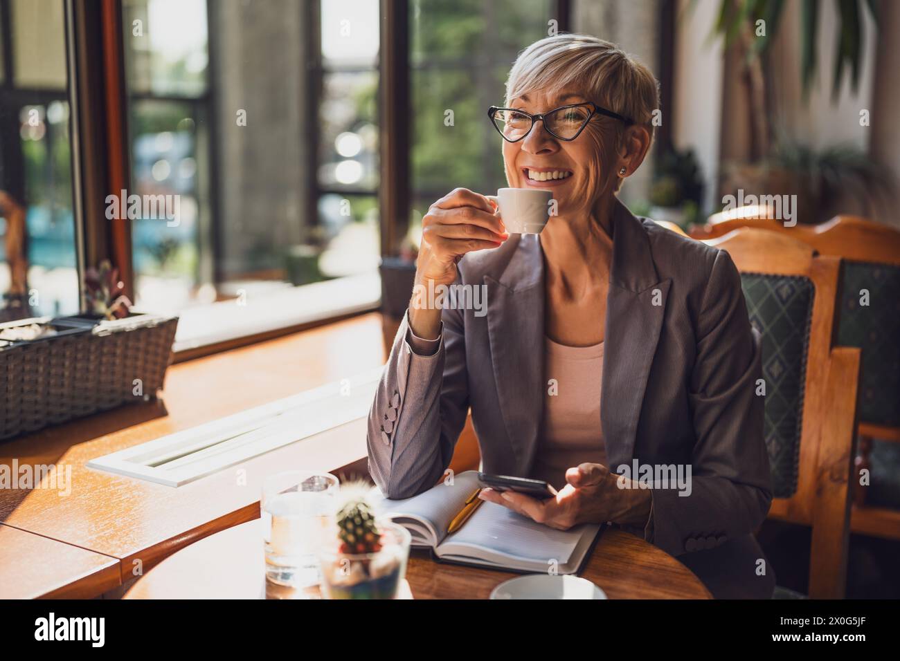 Una donna matura è seduta in una caffetteria e si sta rilassando. Foto Stock
