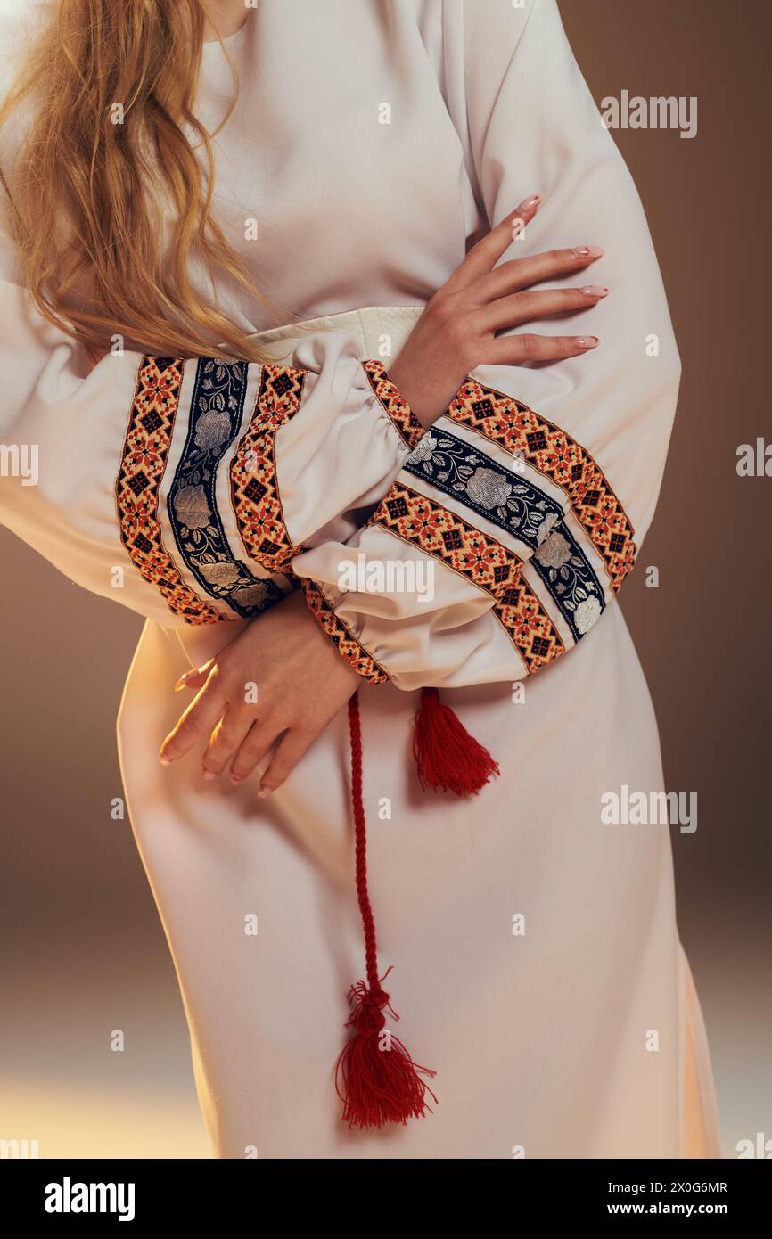 Una giovane Mavka in uno splendido abito bianco impreziosito da una vivace nappina rossa, che incarna una presenza simile a una fiaba in un ambiente da studio. Foto Stock