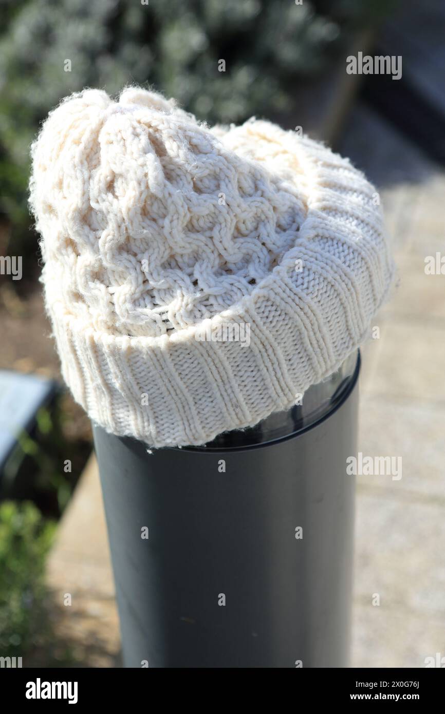 Cappello bianco in lana su un concetto post-riscaldamento, mantenimento dell'inverno caldo, costo del riscaldamento delle bollette energetiche di crisi Foto Stock