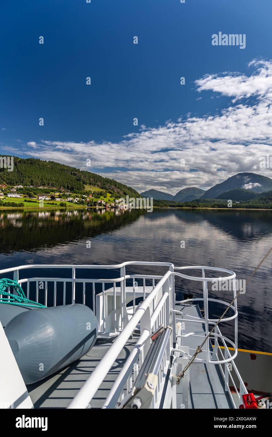 Ponte dei traghetti con vista sulle tranquille acque e le montagne intorno al villaggio di Kvanne sul fiordo Stangvikfjord, nuvole bianche del cielo blu in Norvegia Foto Stock