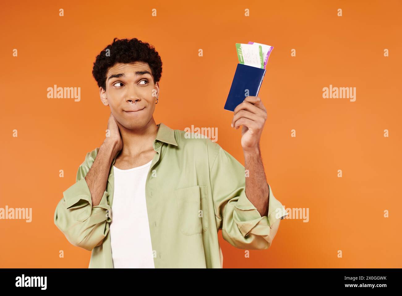 bell'uomo afro-americano che guarda biglietti e passaporto in mano sullo sfondo arancione Foto Stock