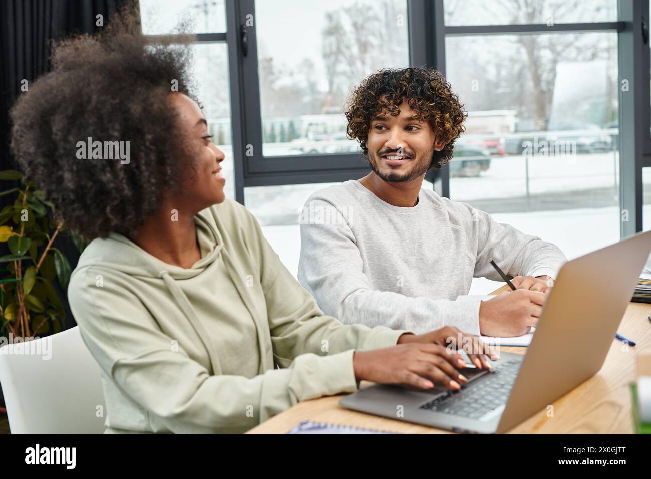 Gli studenti multiculturali partecipano a studi collaborativi a un tavolo con un notebook in un moderno spazio di coworking. Foto Stock