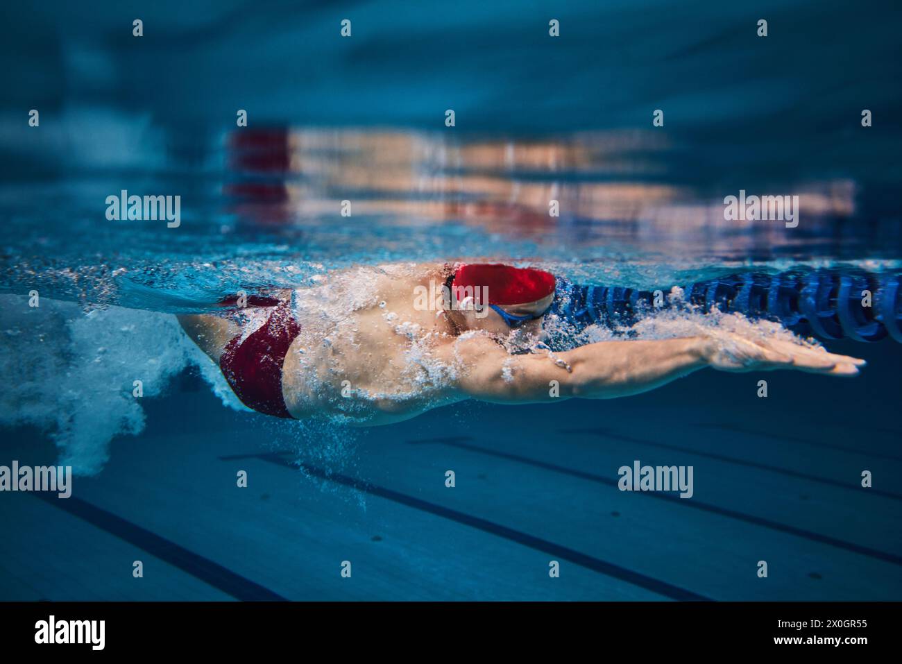 Giovane muscoloso, nuotatore in movimento, preparazione alla competizione, allenamento in piscina al coperto. Velocità e tecnica Foto Stock