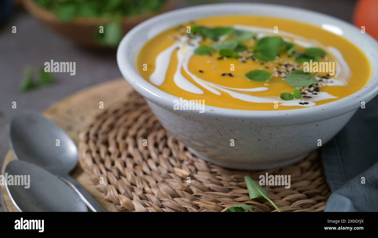 Deliziosa zuppa di zucca cremosa fatta in casa con panna con semi di sesamo e crescione. Foto Stock