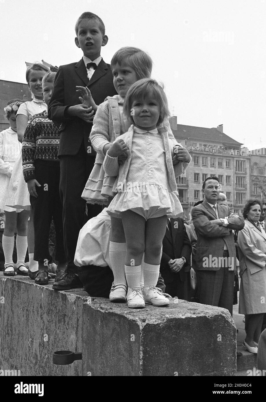 Kinder stehen auf einer Mauer, damit sie eine bessere Sicht auf das Geschehen haben. Im Hintergrund sind weitere Zuschauer zu sehen. (Aufnahmedatum: 01.01.1960-31.12.1969) Foto Stock